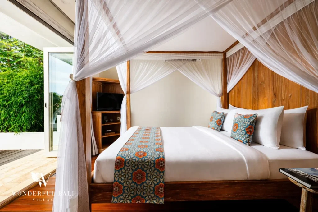 Canopy bed against a wood-panelled wall opening to the garden, Villa Hasian — 5-bedroom villa in Jimbaran