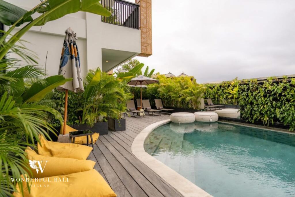 Shared pool with sun loungers, umbrella and bean bags, modern apartment building in Canggu
