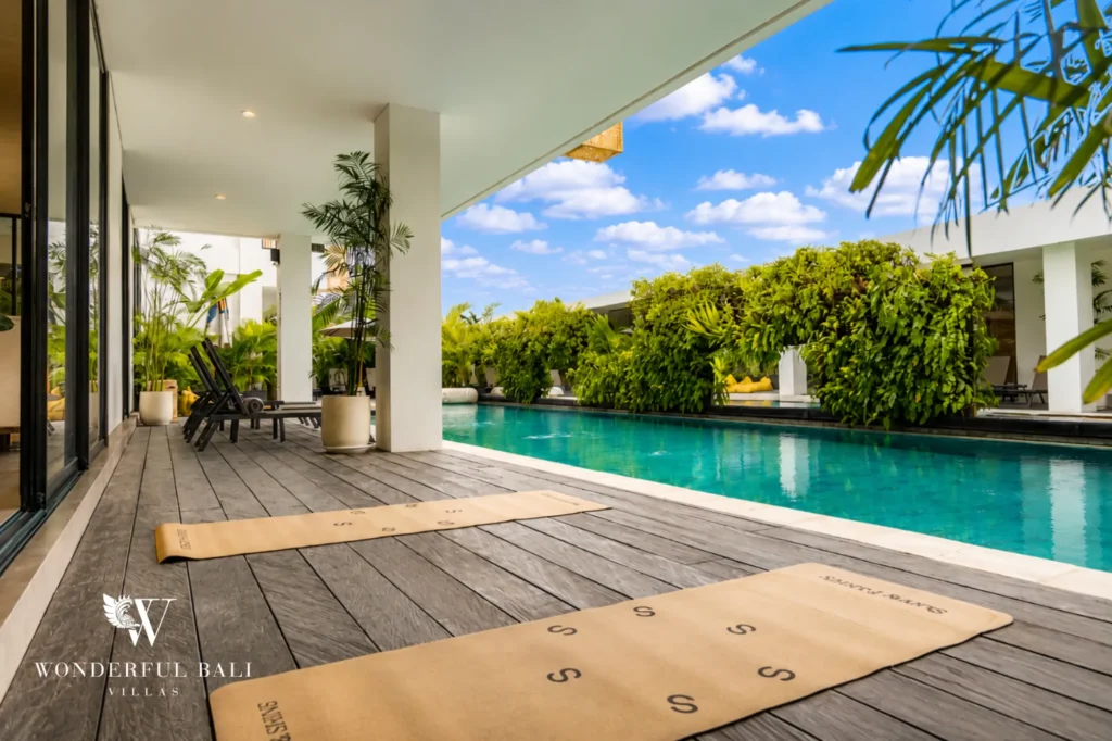 Shared pool deck framed by a palm tree, modern serviced apartment in Canggu, Bali