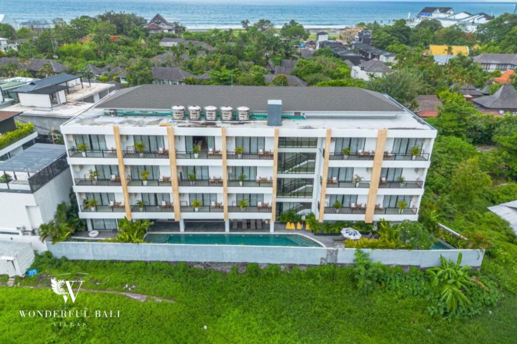 Aerial view of a modern apartment building with pool and ocean backdrop, Canggu, Bali