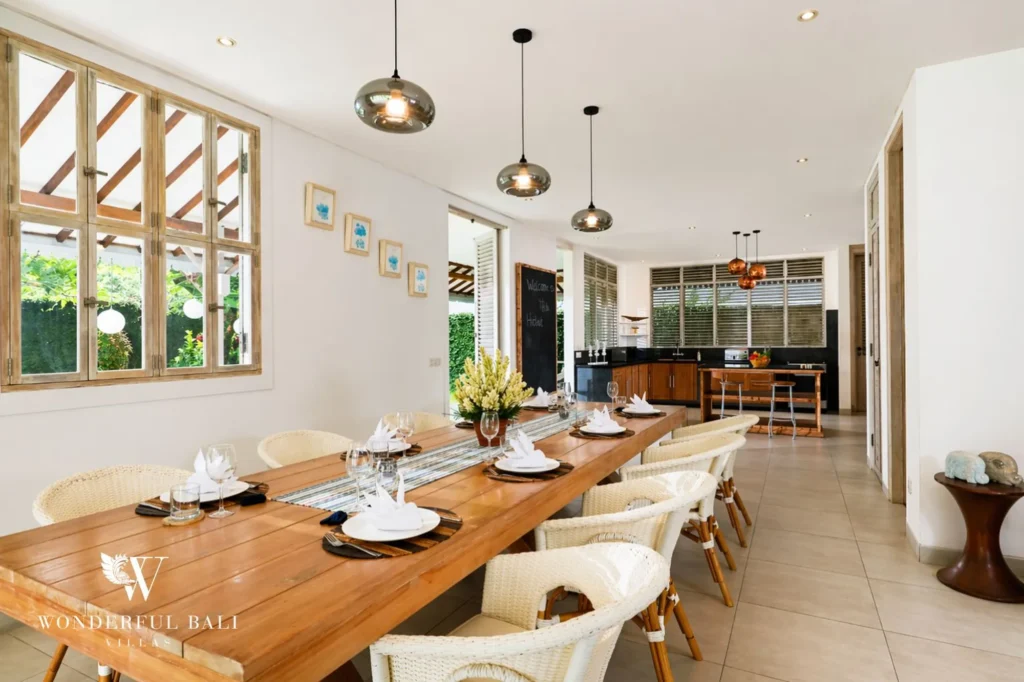 Long dining table set for a meal with the kitchen beyond, Villa Hasian in Jimbaran