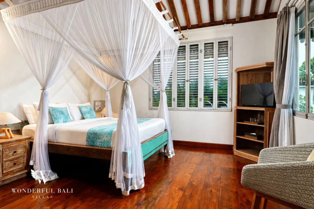Canopy bed in a traditional Balinese bedroom with TV and shutters, Villa Hasian in Jimbaran