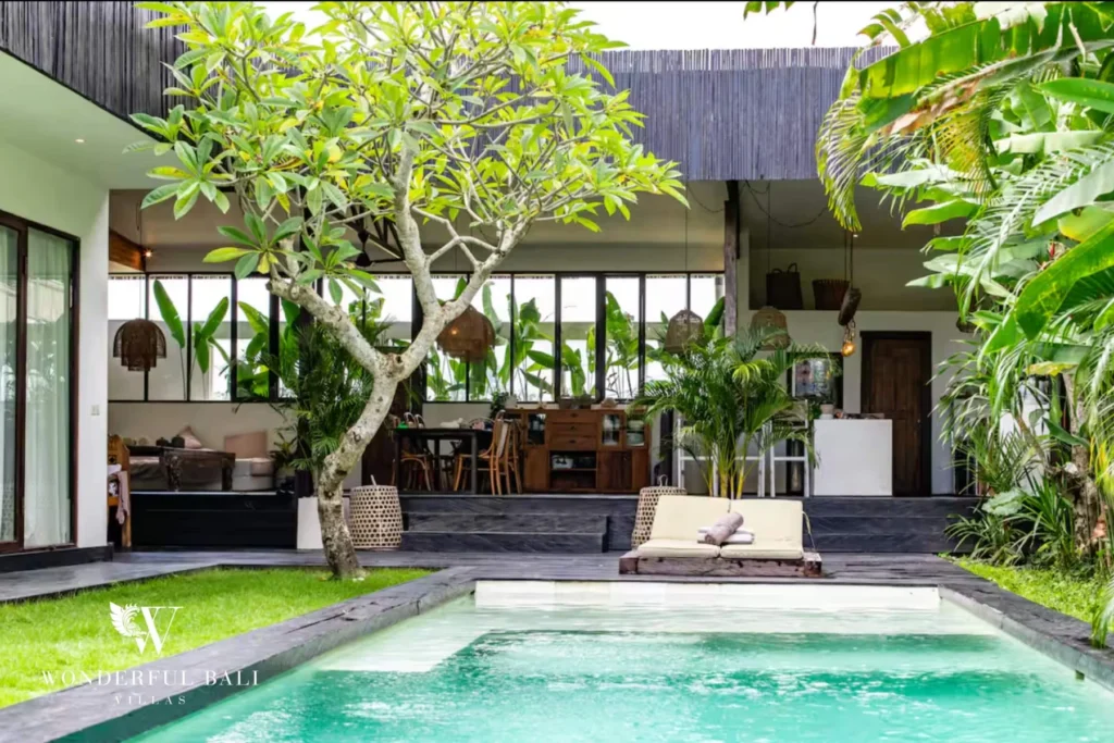 Tropical private pool with frangipani tree and glass-walled living pavilion in Umalas, Bali