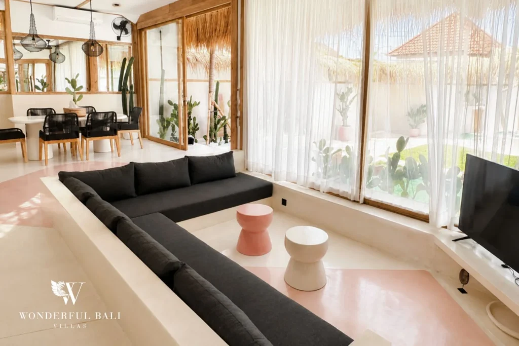 Boho sunken lounge with charcoal sofas and pink terrazzo stools in Berawa, Bali