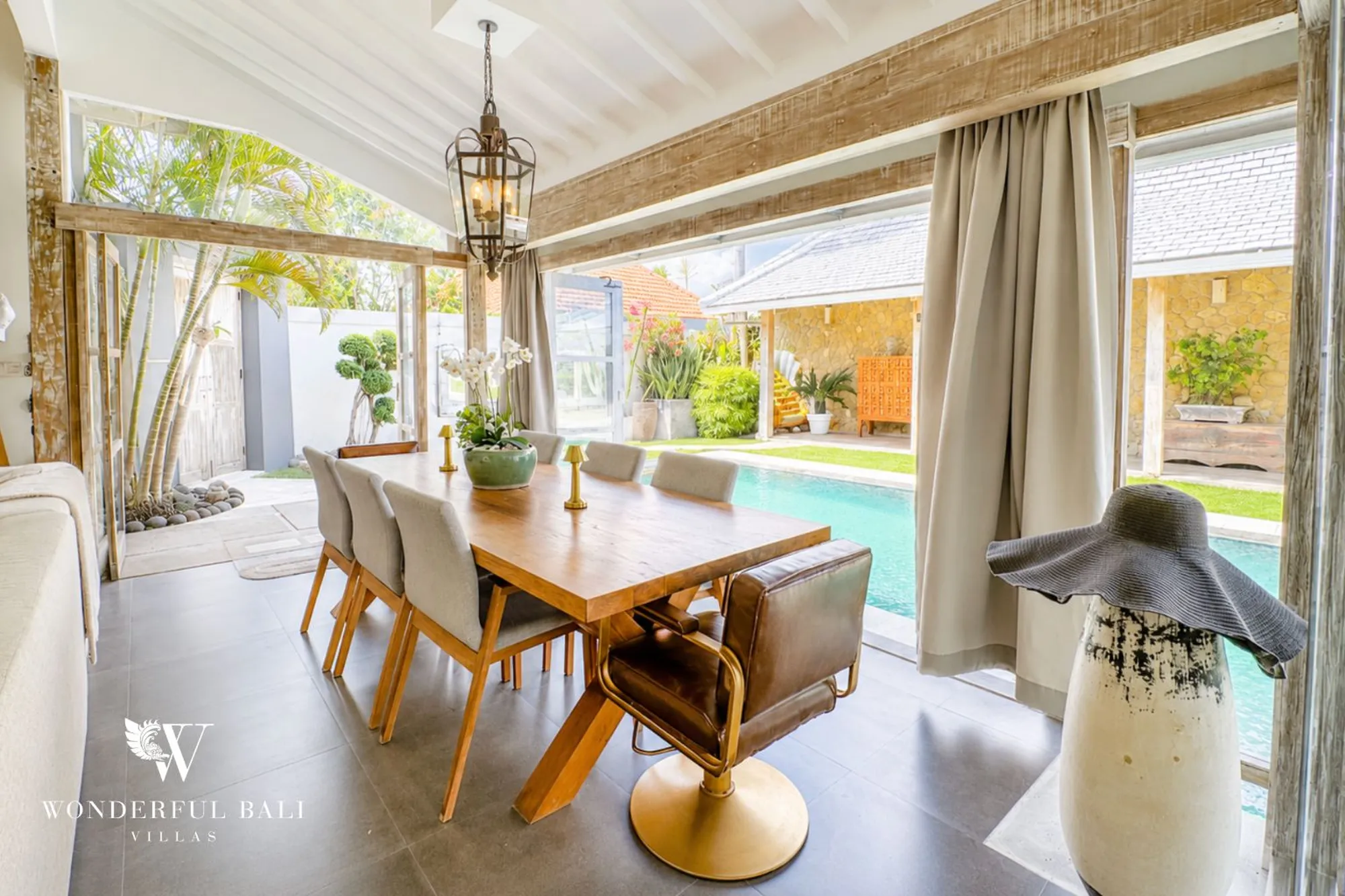 Covered villa terrace with a dining table beside a private pool in Bali