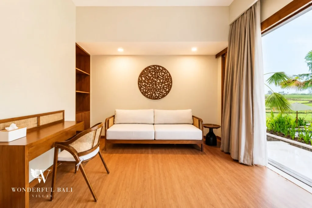 Bedroom lounge with carved wall art and rice field view in Tumbak Bayuh, Bali