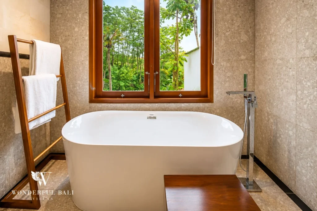 Bathroom with freestanding bathtub and jungle window view in Tumbak Bayuh, Bali