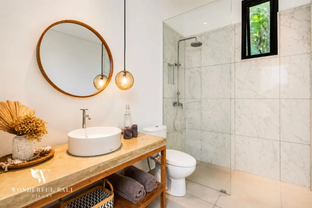 Bathroom with round mirror and modern vanity, 4-bedroom family villa in Berawa, Canggu