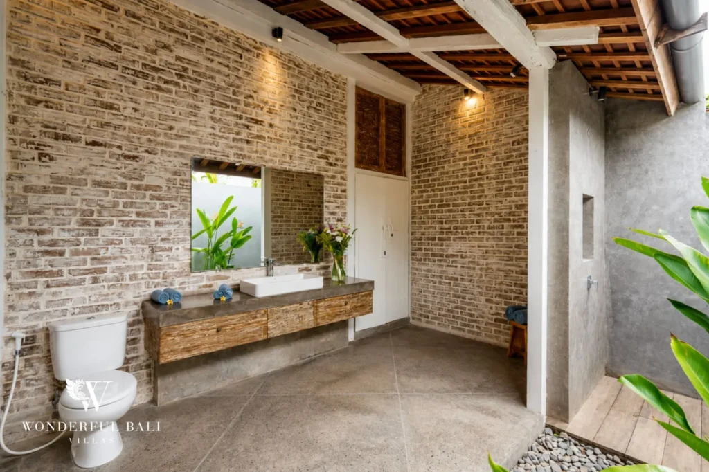 Bathroom with natural stone vanity and exposed brick, dual-villa compound in Pererenan