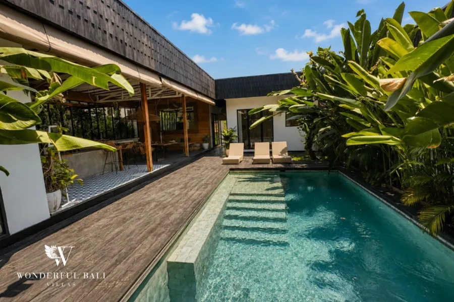 Pool courtyard with thatched roof and lush tropical plants at villa in Canggu, Bali