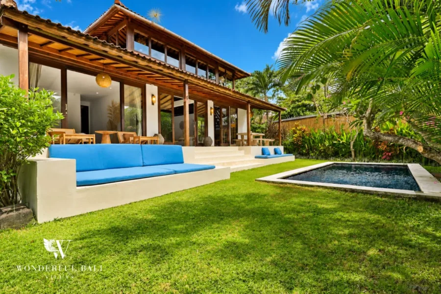 Pool with garden lawn and timber-pavilion villa exterior at villa in Umalas, Bali