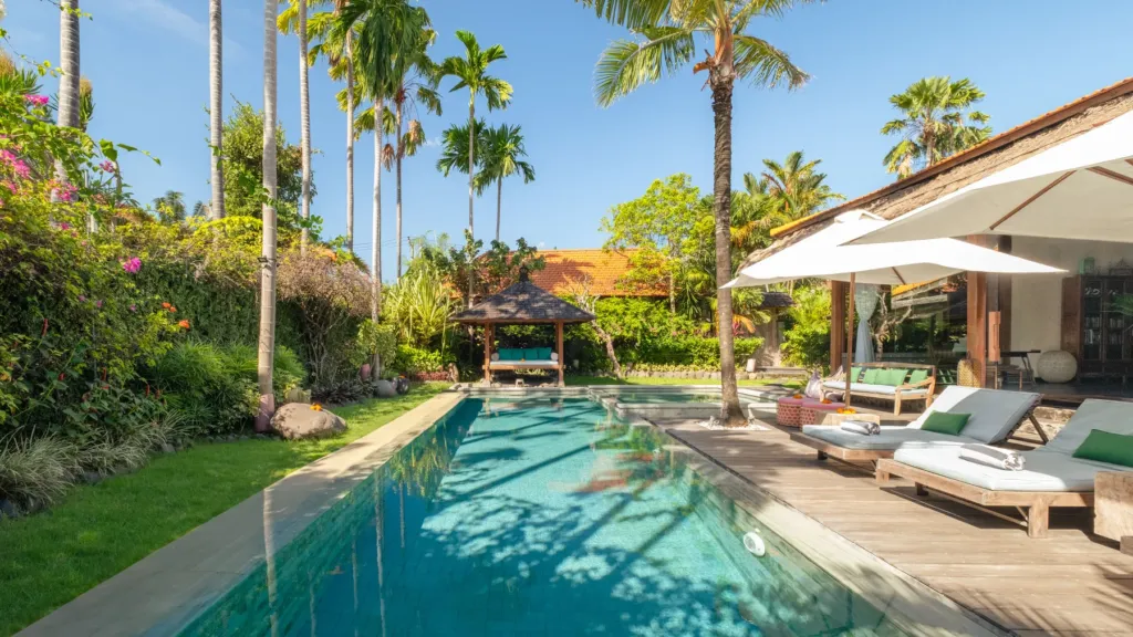 Pool and tropical garden with sun loungers at Villa Desa Roro Dua, Berawa