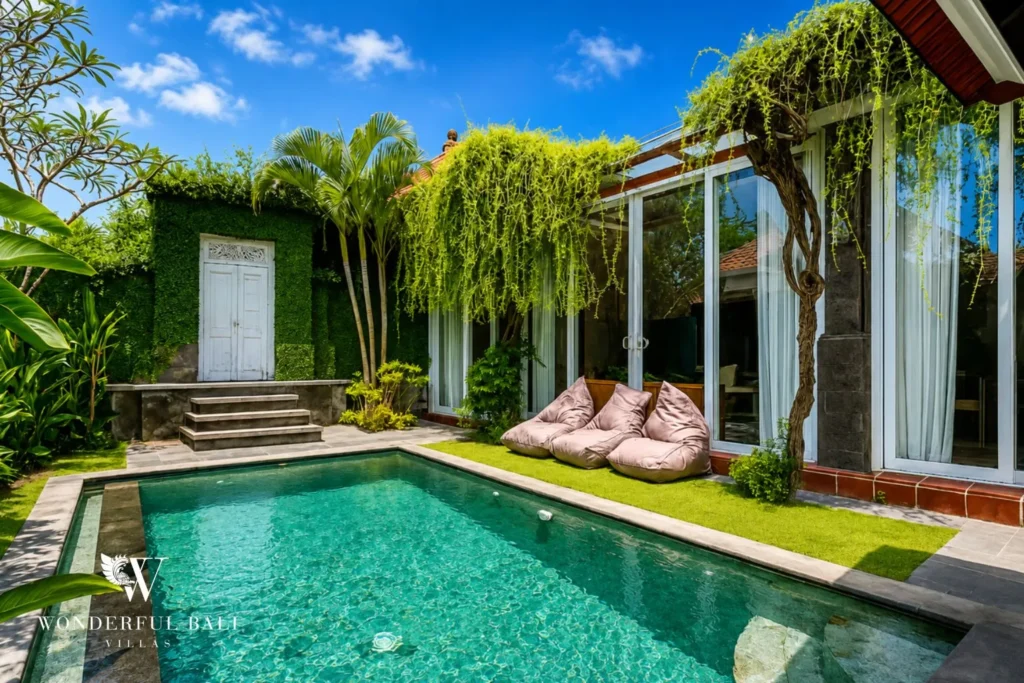Pool with sun loungers framed by lush tropical garden and villa at villa in Canggu, Bali