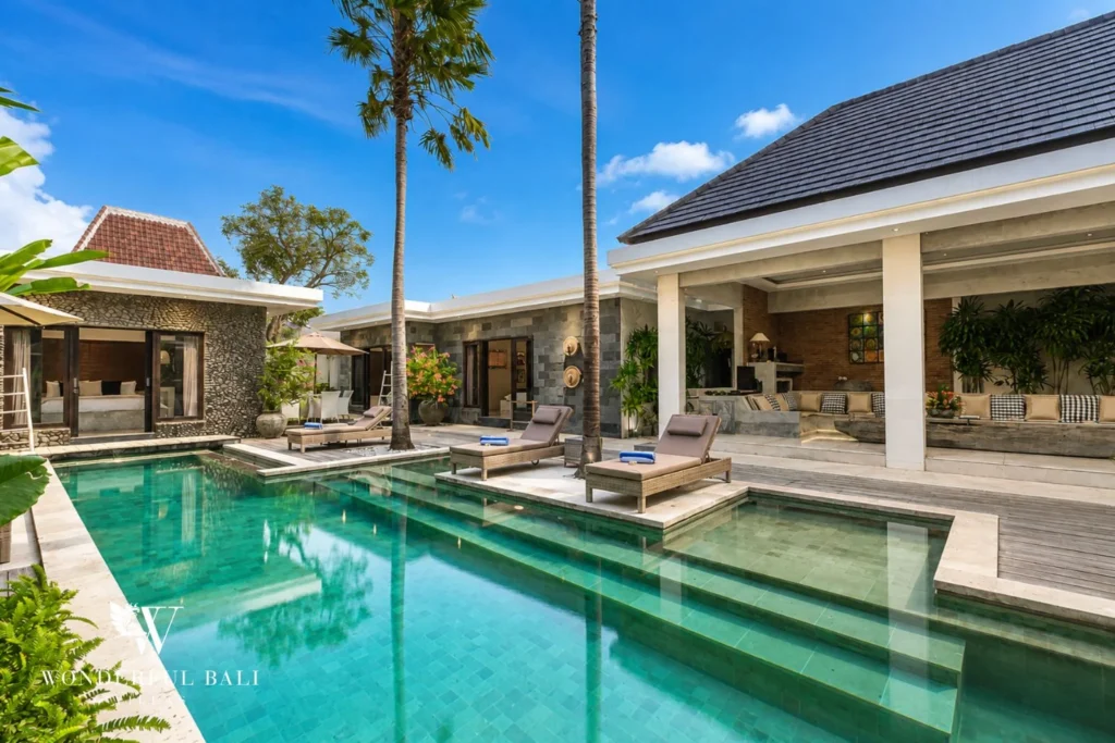 Lap pool with sun-deck platform and palms at tropical pavilion villa in Seminyak, Bali