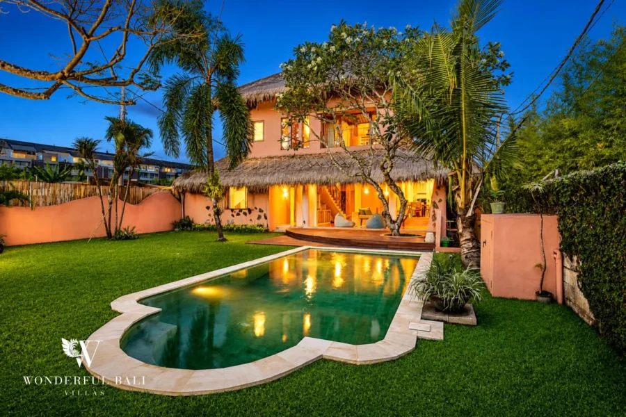 Pool and two-storey villa lit at evening with lawn at villa in Bumbak, Bali