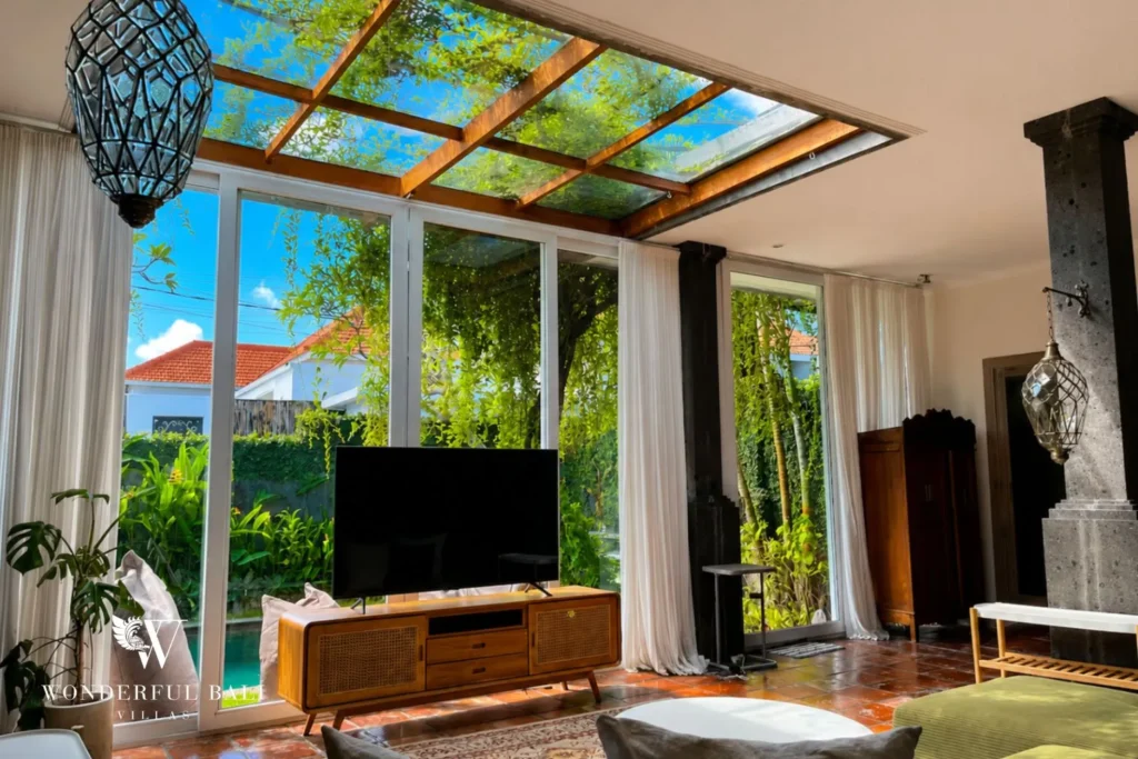 Open-air living area with sofa, TV and sliding doors to the garden at villa in Canggu, Bali