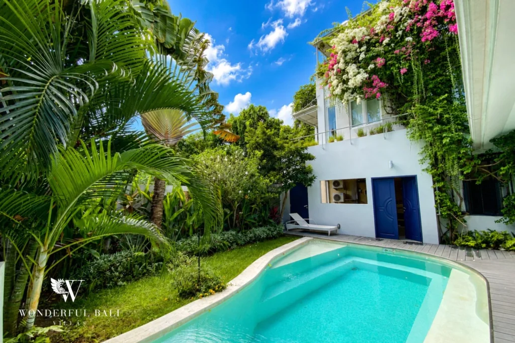 Pool with cobalt-blue doors and tropical garden at industrial villa in Umalas, Bali