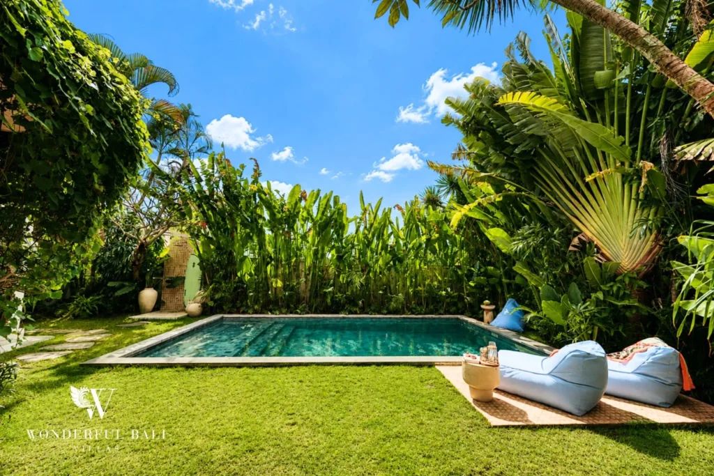 Pool with lawn, daybed and dense tropical garden at villa in Berawa, Bali