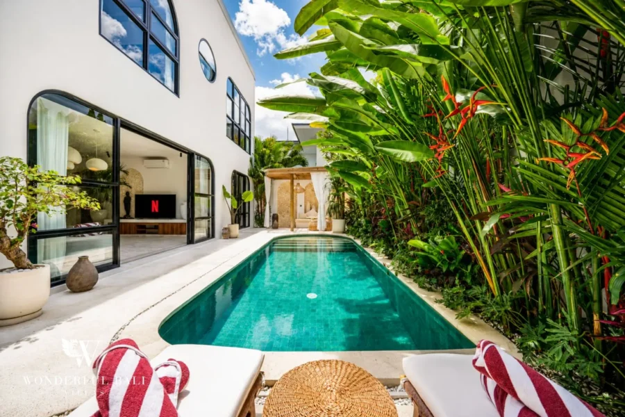 Pool with sun loungers framed by lush jungle garden at villa in Umalas, Bali