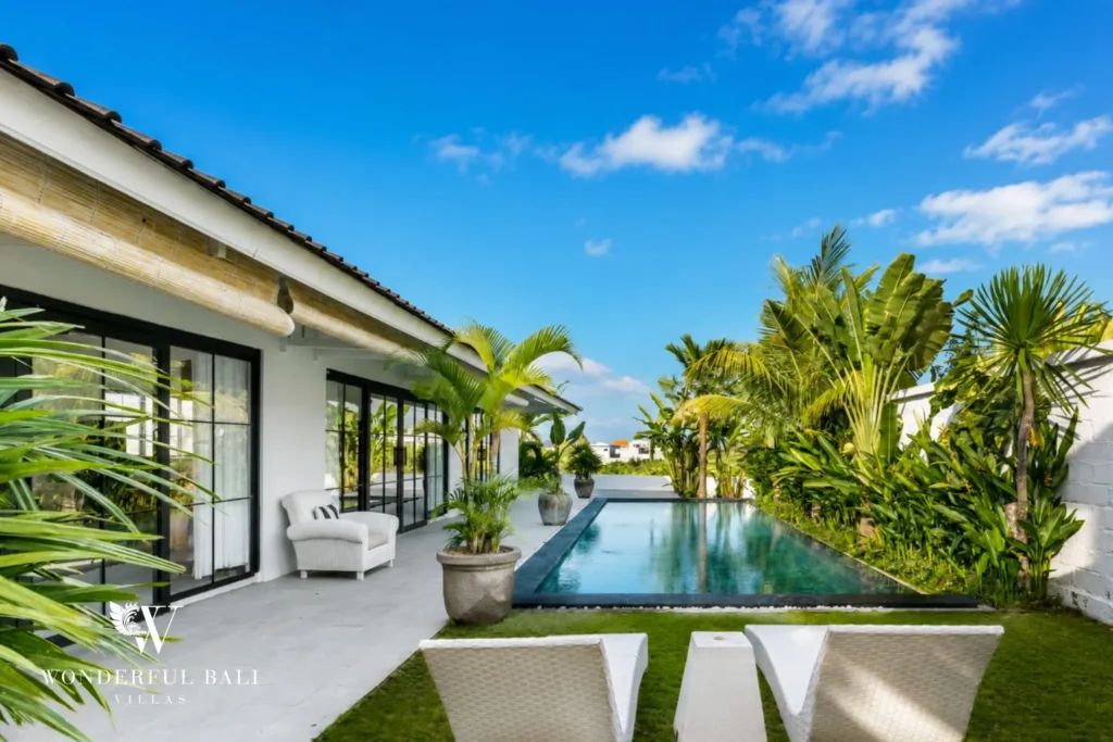Pool with sun loungers, lawn and villa facade at villa in Canggu, Bali