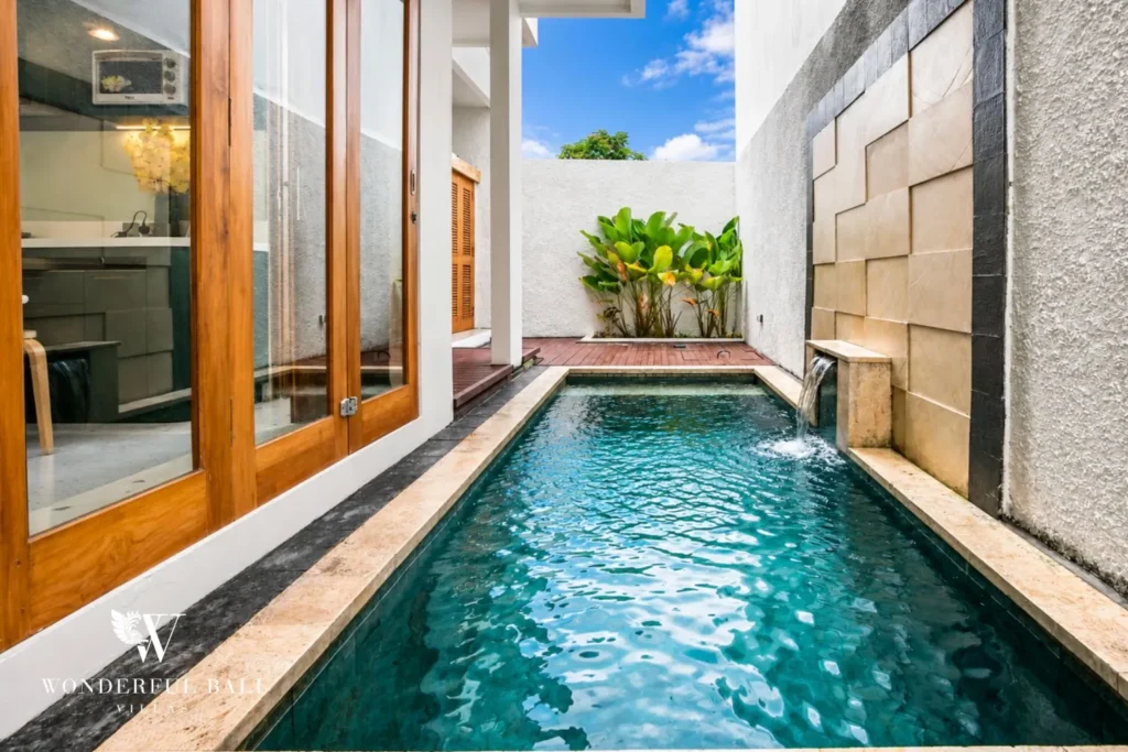 Lap pool beside a stone feature wall and glass doors at villa in Denpasar, Bali