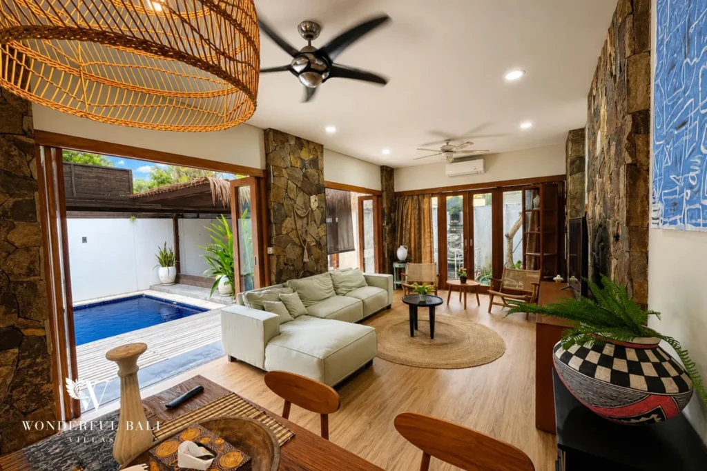 Living area with rattan seating and glass doors opening to the pool at villa in Berawa, Bali
