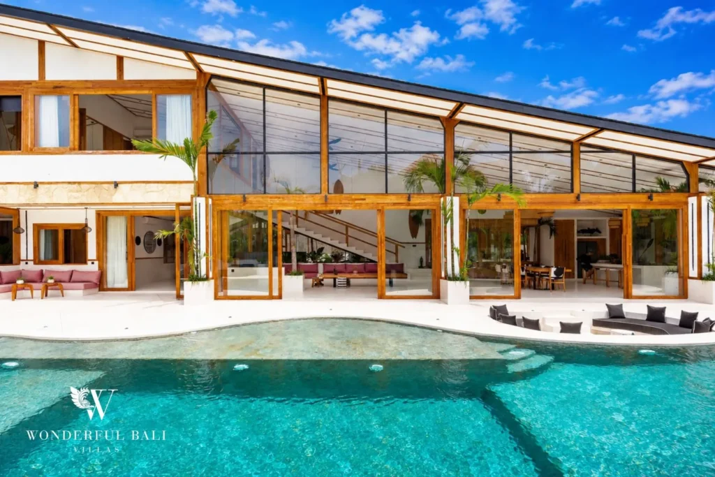 Private pool with glass facade and sun loungers at family villa in Umalas, Bali