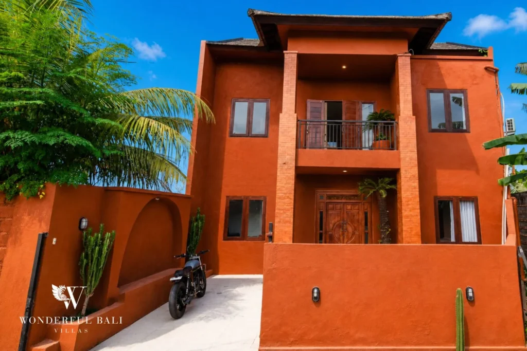 Terracotta two-storey villa facade with traditional carved door in Nyanyi, Bali