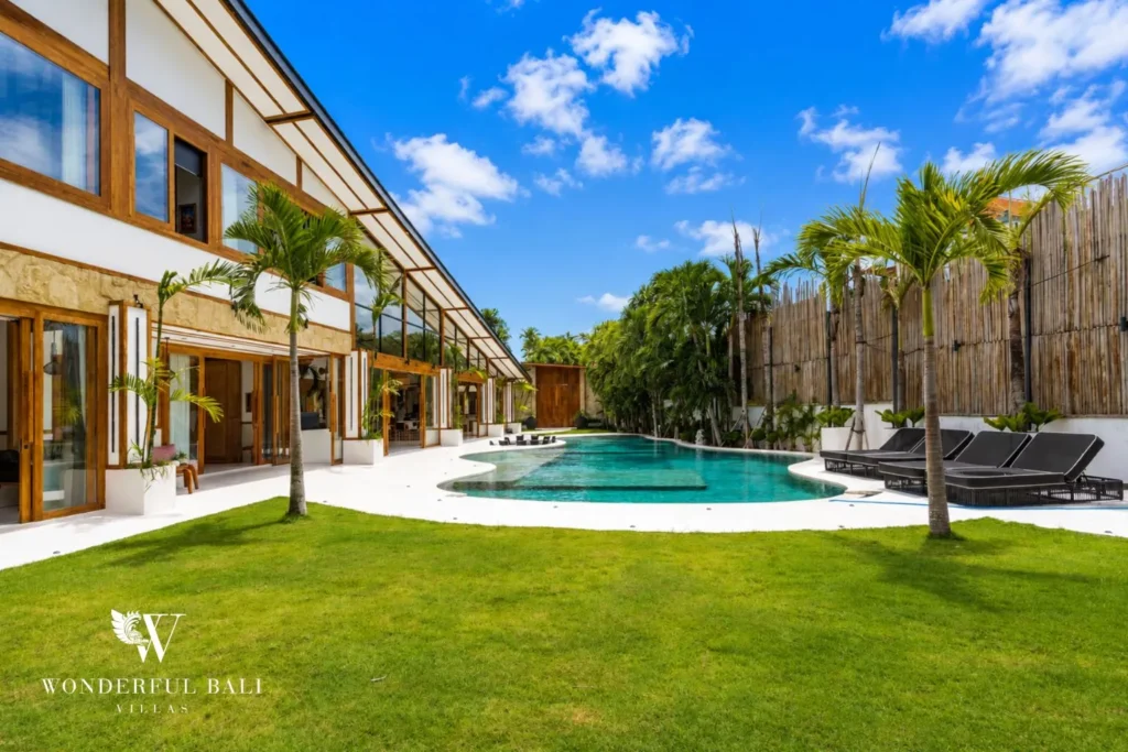 Lap pool with garden lawn and villa exterior at family villa in Umalas, Bali