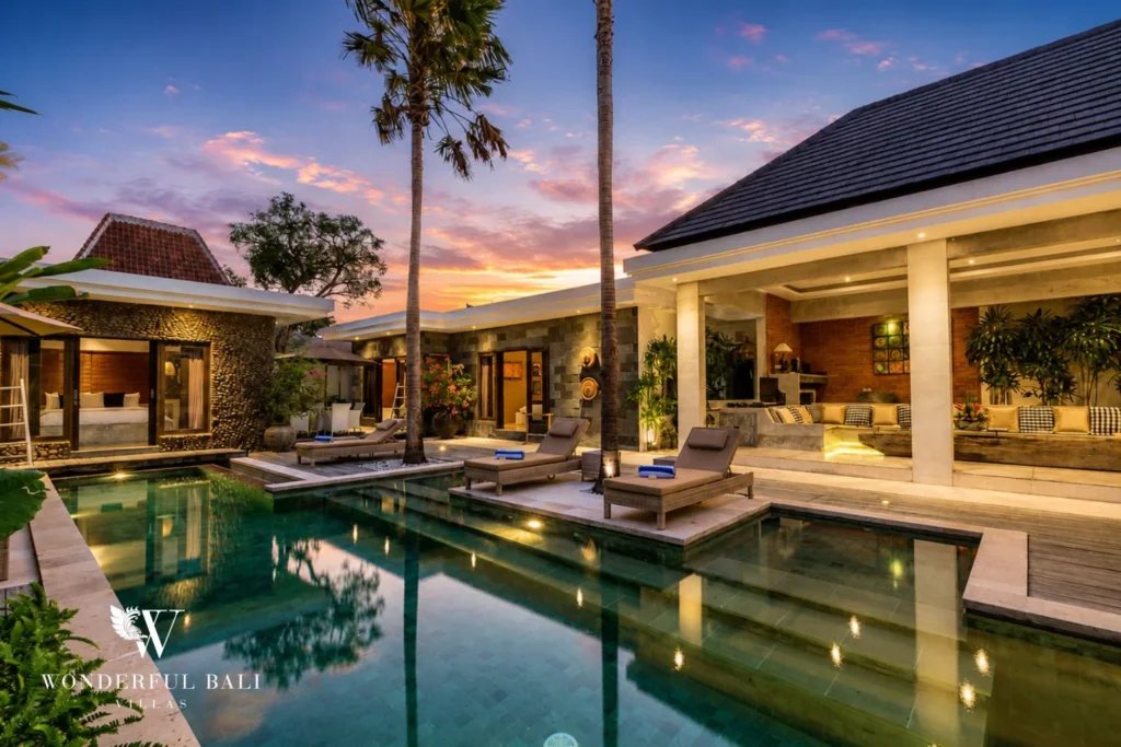 Open-air living pavilion with long sectional and lava stone wall at villa in Seminyak, Bali