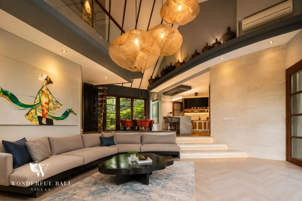 Open-plan living and kitchen with sofa, artwork and pendant lights at villa in Umalas, Bali