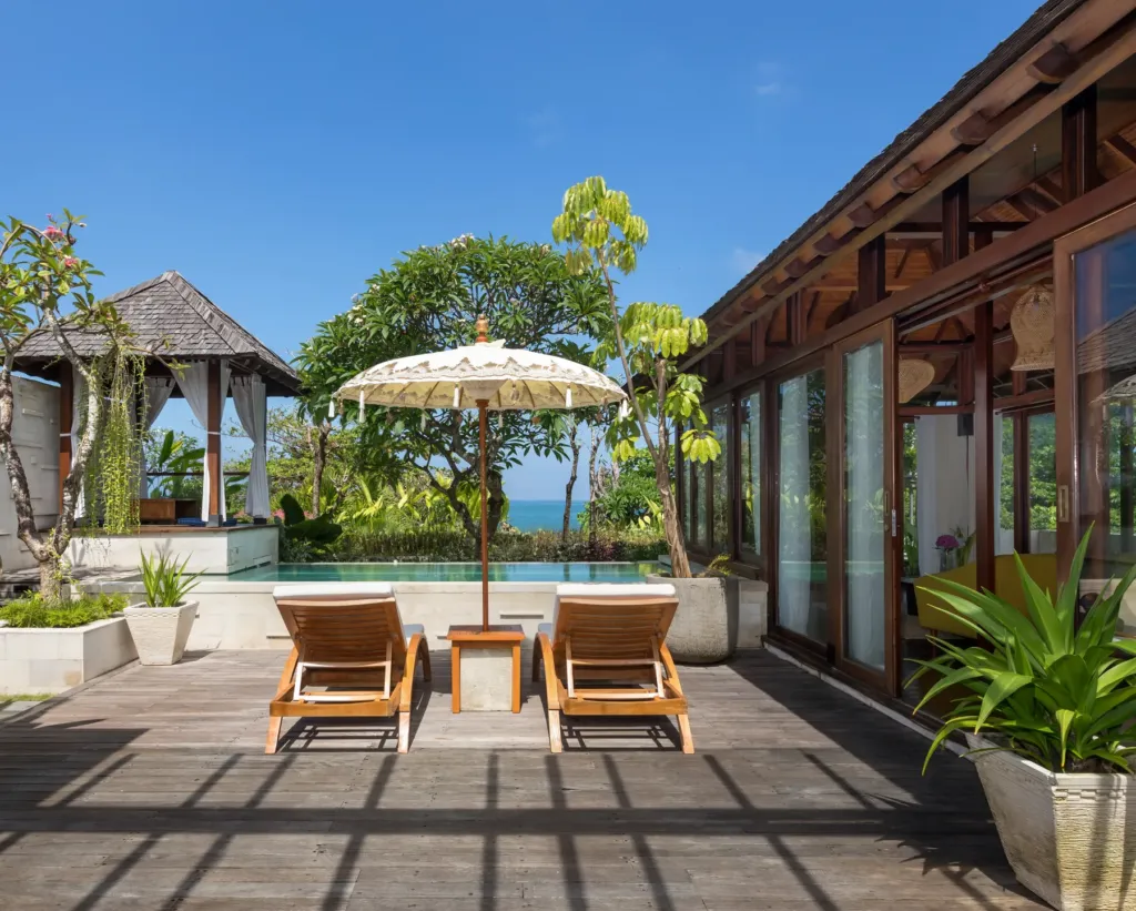 Pool with outdoor dining bale and umbrella in daylight at villa in Batu Belig, Bali