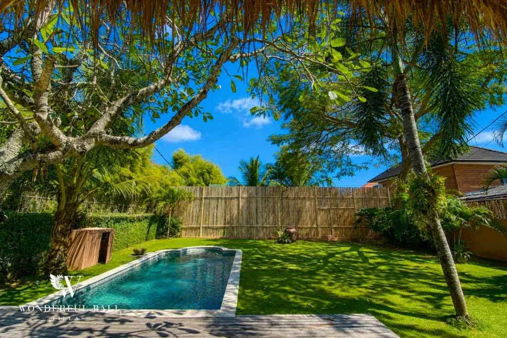 Pool surrounded by garden and lawn in daylight at villa in Bumbak, Bali