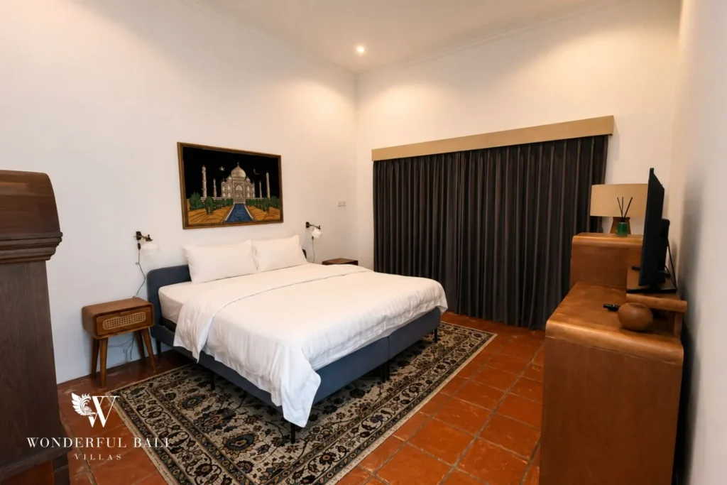 Bedroom with white bed, dark headboard and patterned rug at villa in Canggu, Bali