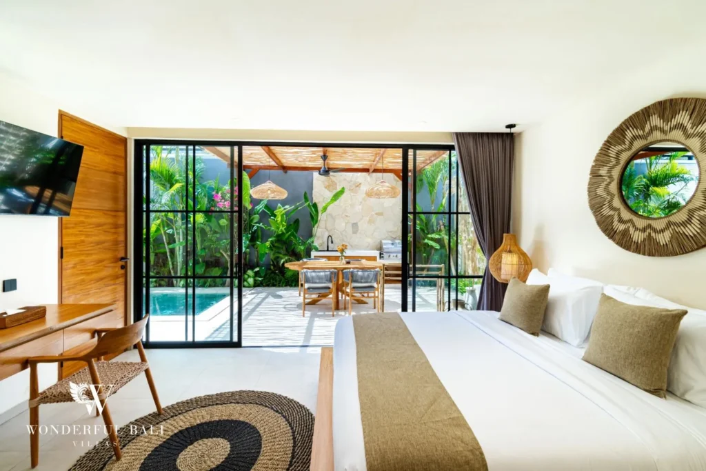 Bedroom with glass doors, round mirror and plants at villa in Seseh, Bali