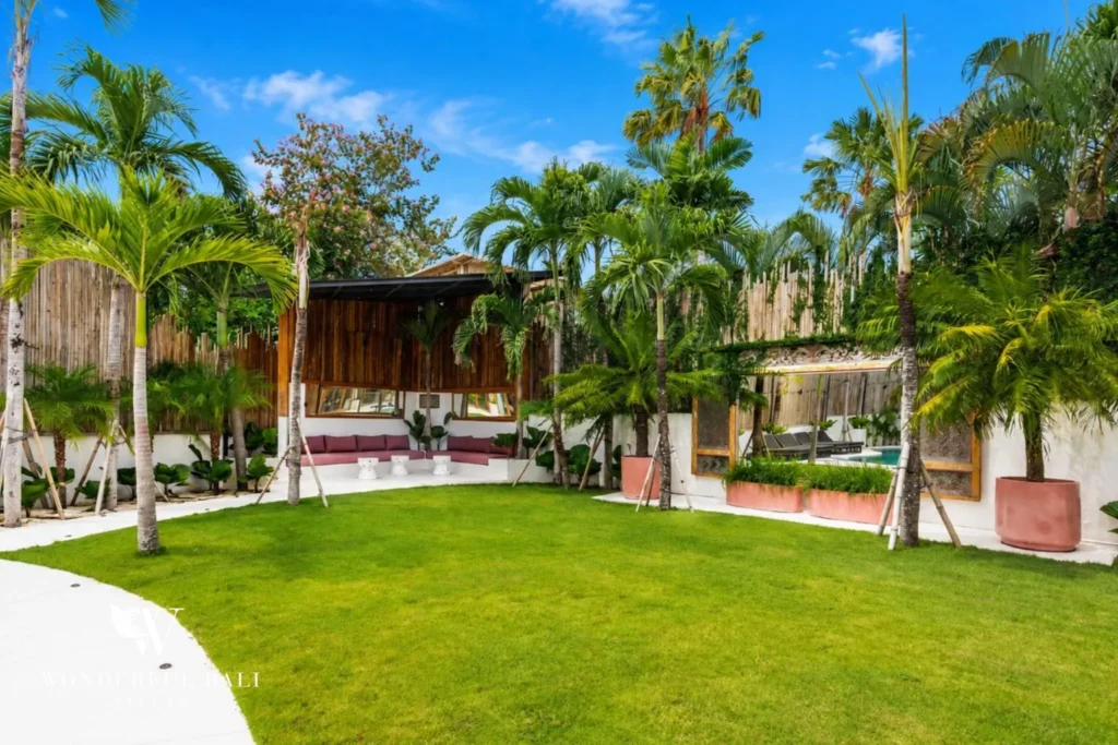 Tropical garden and pool framed by palm trees at family villa in Umalas, Bali