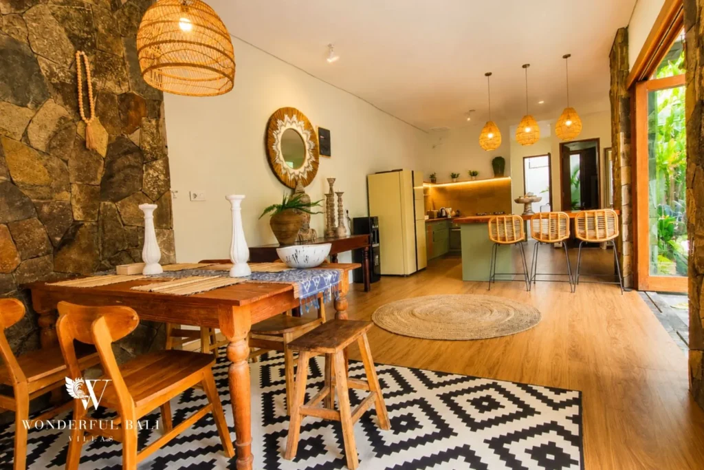 Dining table with rattan pendants against a stone feature wall at villa in Berawa, Bali