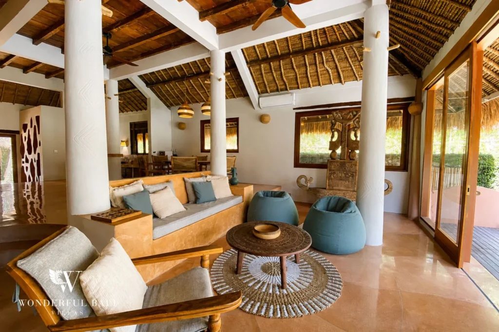 Living area with beanbags and thatched ceiling open to garden at villa in Bumbak, Bali