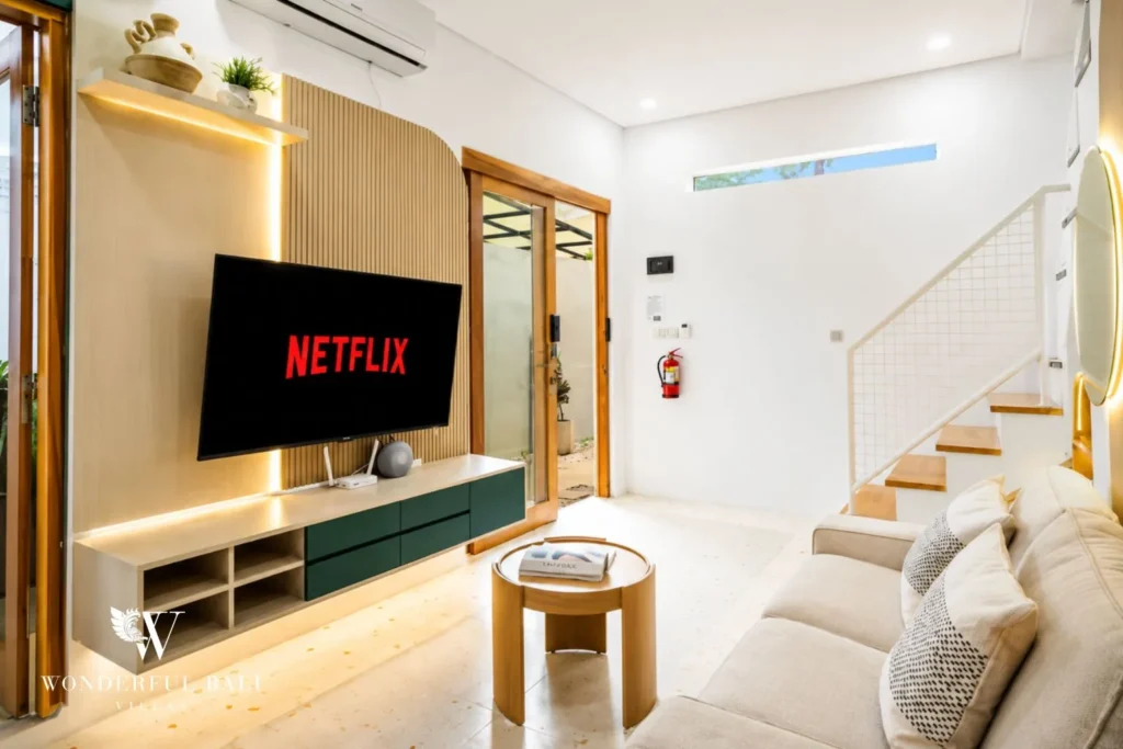 Living area with sofa, TV and open staircase at villa in Denpasar, Bali