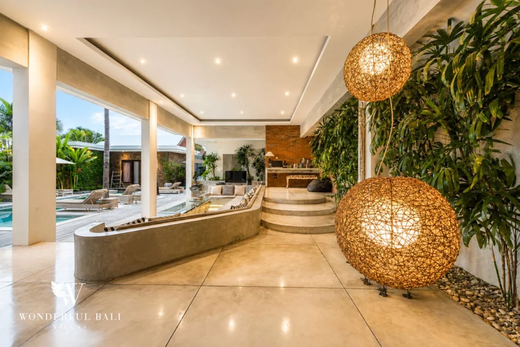 Pool at dusk with frangipani, lit pavilions and central sun-deck at villa in Seminyak, Bali