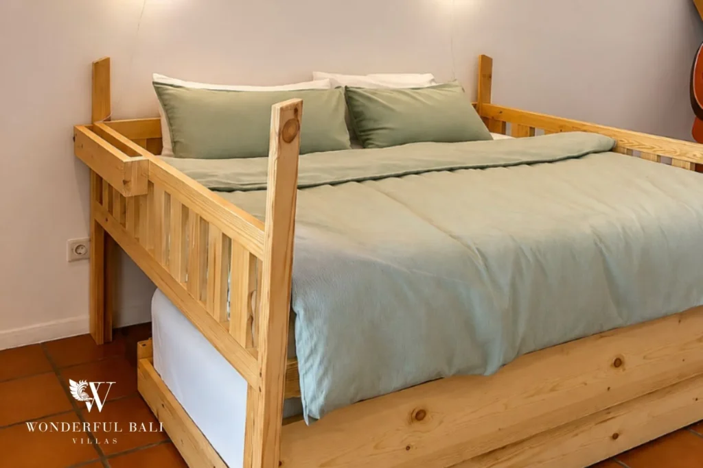 Bedroom with carved wooden bed against a green accent wall at villa in Canggu, Bali