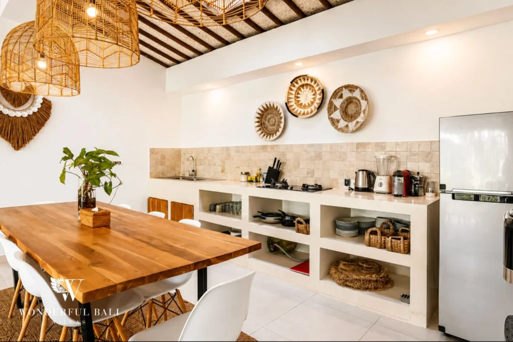 Dining area with woven wall decor and open kitchen at villa in Umalas, Bali