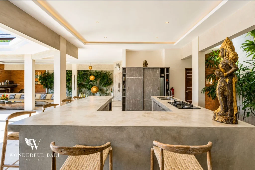 Open kitchen with concrete island, gold Buddha statue and lava wall at villa in Seminyak, Bali