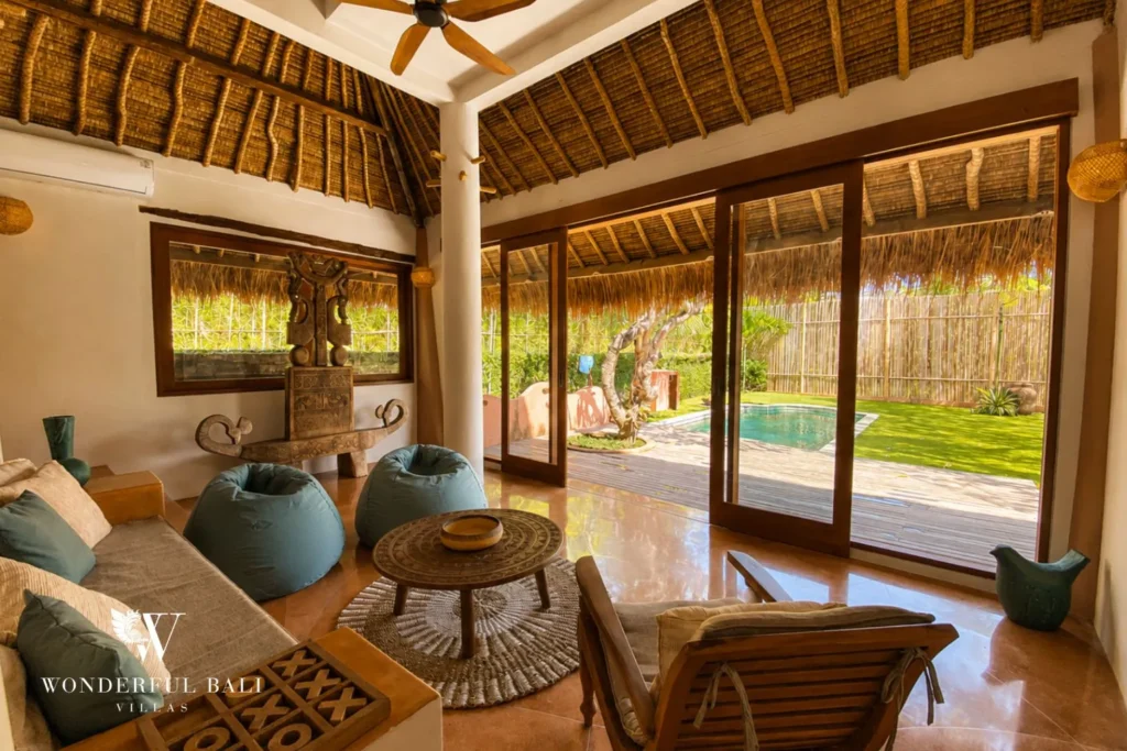 Living lounge with rattan chairs and glass doors to garden at villa in Bumbak, Bali