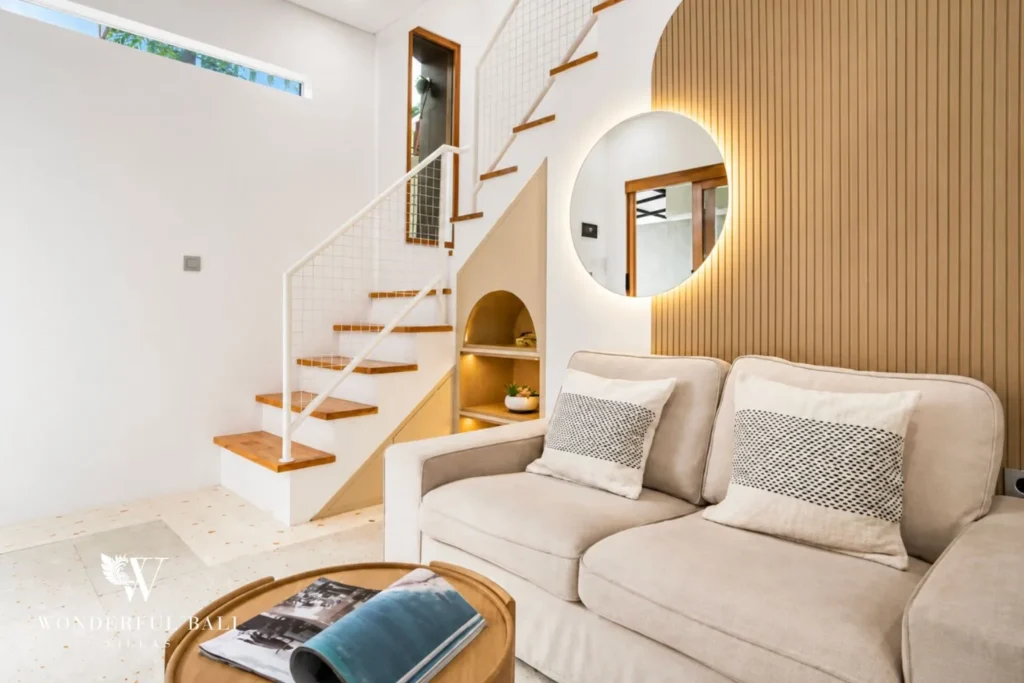 Living lounge with sofa, staircase and arched mirror at villa in Denpasar, Bali