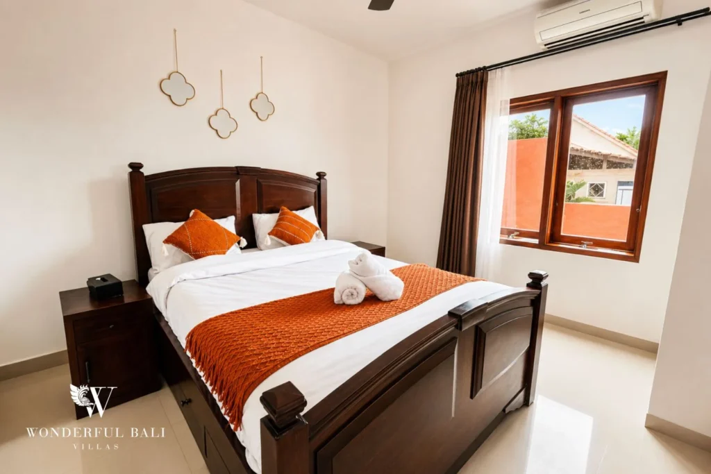 Master bedroom with traditional wooden bed and orange accents in Nyanyi, Bali