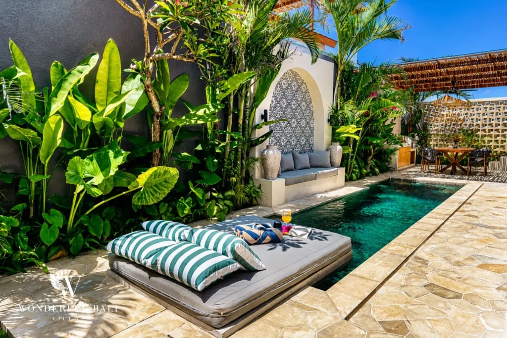Pool with striped daybed and lush plants at villa in Seseh, Bali