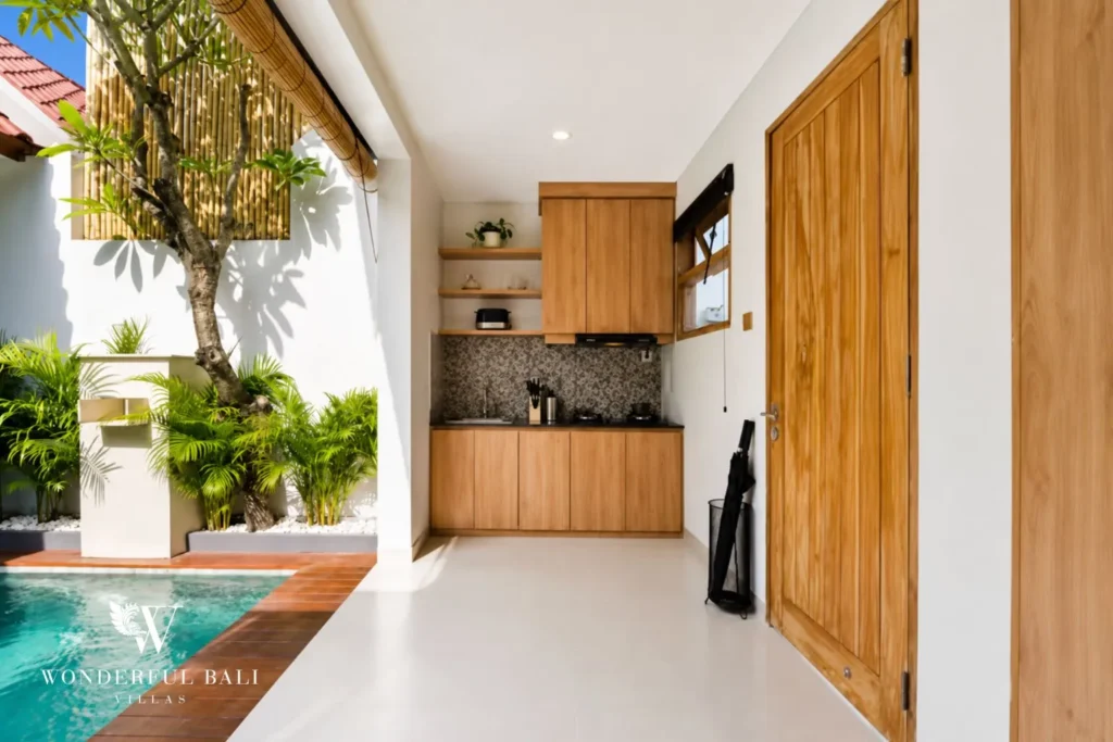 Kitchen with timber cabinets and a view to the pool courtyard at villa in Canggu, Bali