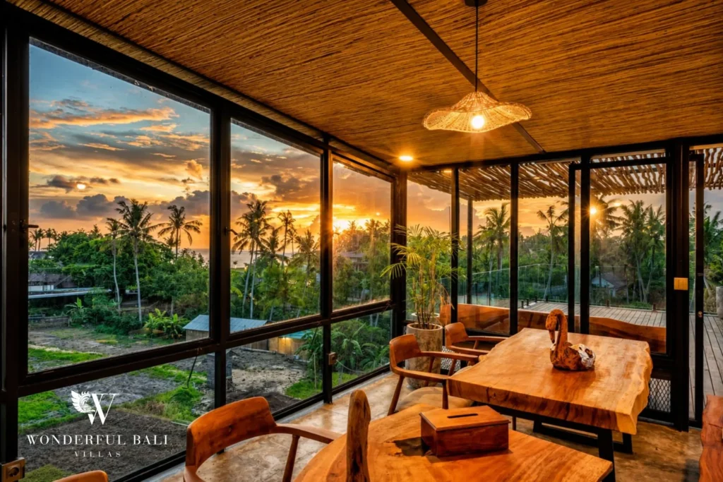 Living and dining area with glass walls at a 4-bedroom ocean-view villa in Seseh, Bali