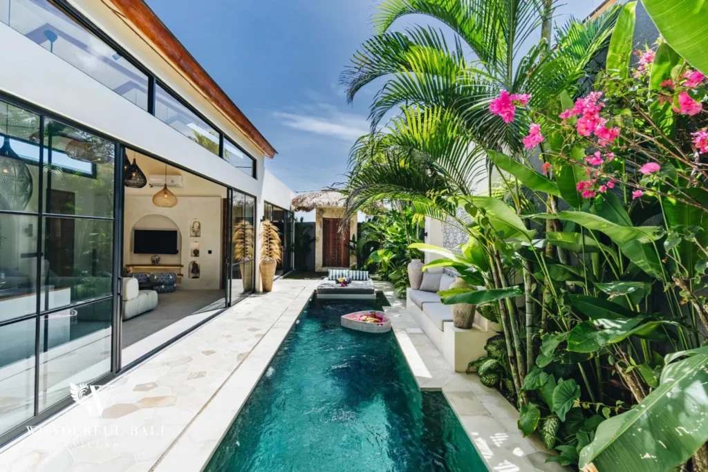 Narrow pool with bougainvillea and glass walls at villa in Seseh, Bali